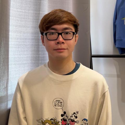 Andrew Bao is standing in the center of the frame facing the camera.