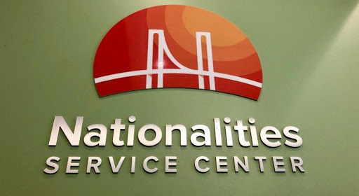 a green wall with an orang half circle logo with a bridge silhouette, under the logo reads Nationalities Service Center